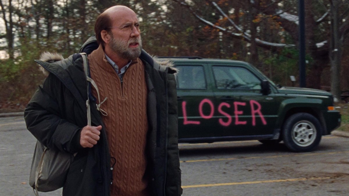 Nicolas Cage angrily stands next to his car on which people have painted Loser in Dream Scenario.