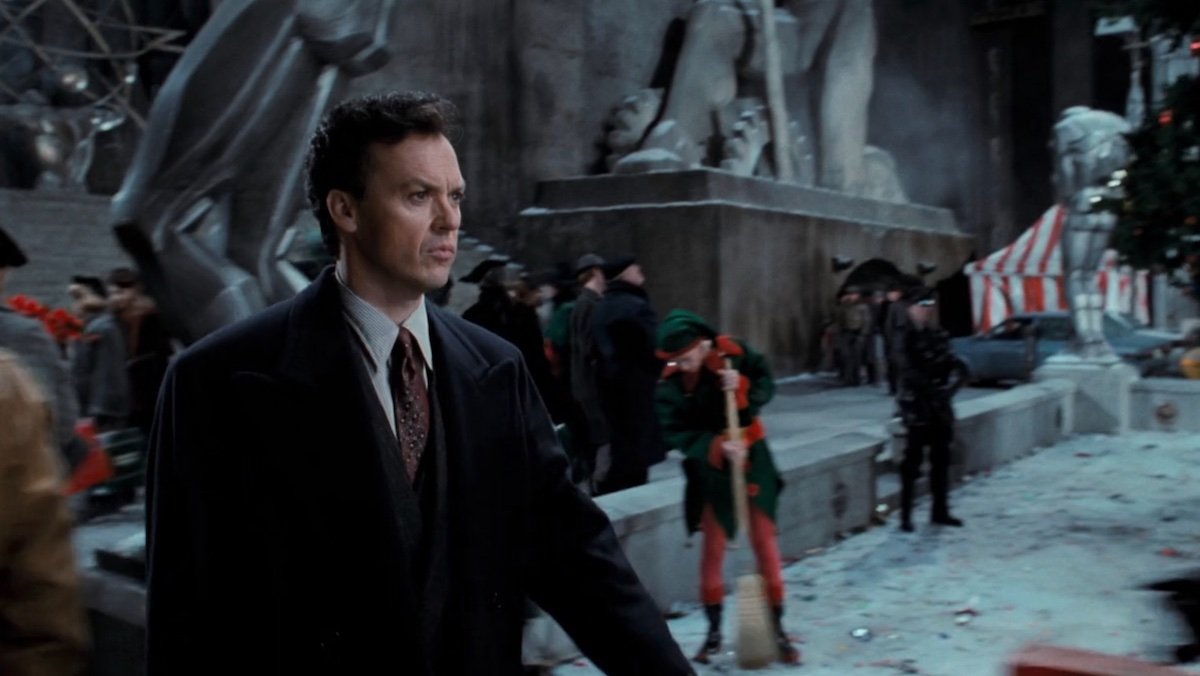 Michael Keaton's Bruce Wayne walks by an elf cleaning up debris in the street in Batman Returns