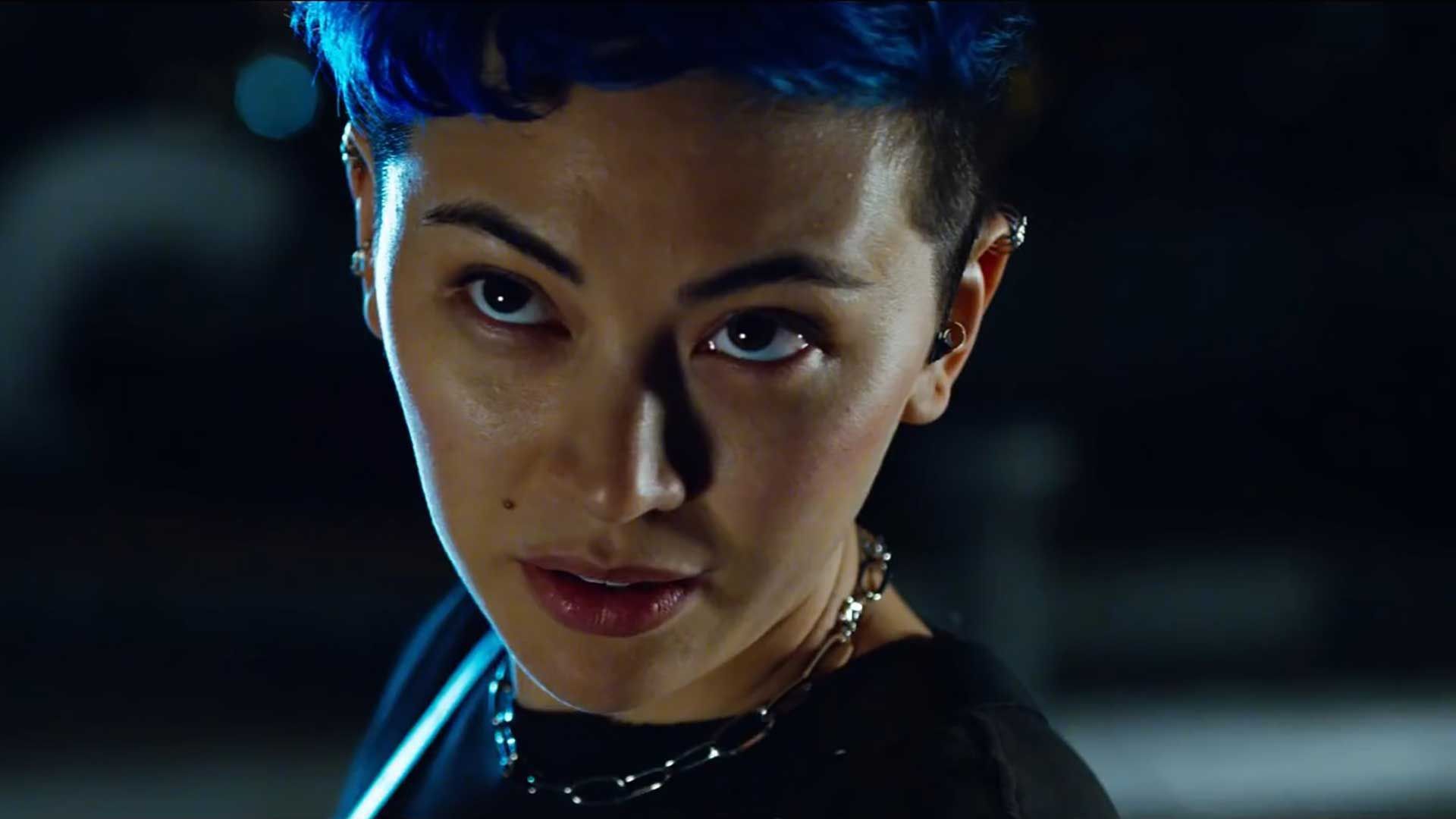 A still from the Matrix Resurrections shows Jessica Henwick as Bugs a young British Asian woman with blue hair