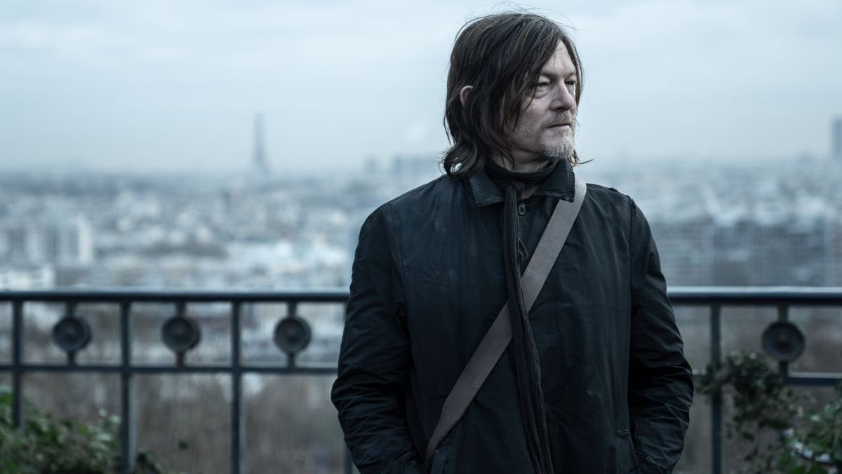 Daryl Dixon stands on a balcony with the Eifel Tower in the background on walking dead tv show