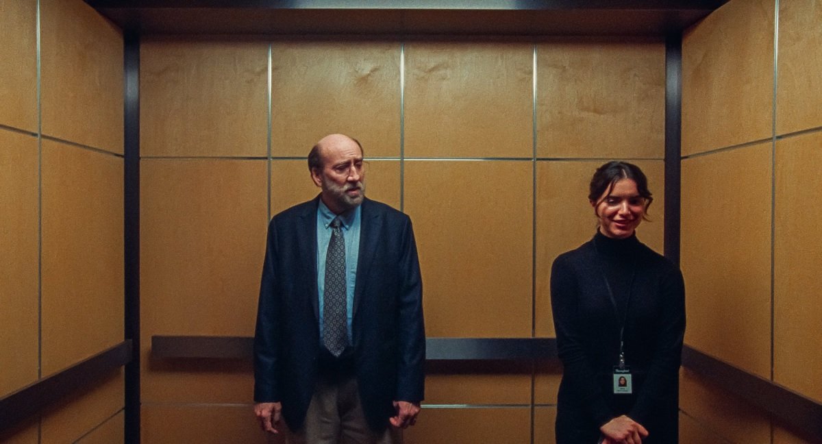 Nicolas Cage stands in an elevator with Dylan Gelula, who is nervous and embarrassed to talk to him, in Dream Scenario.