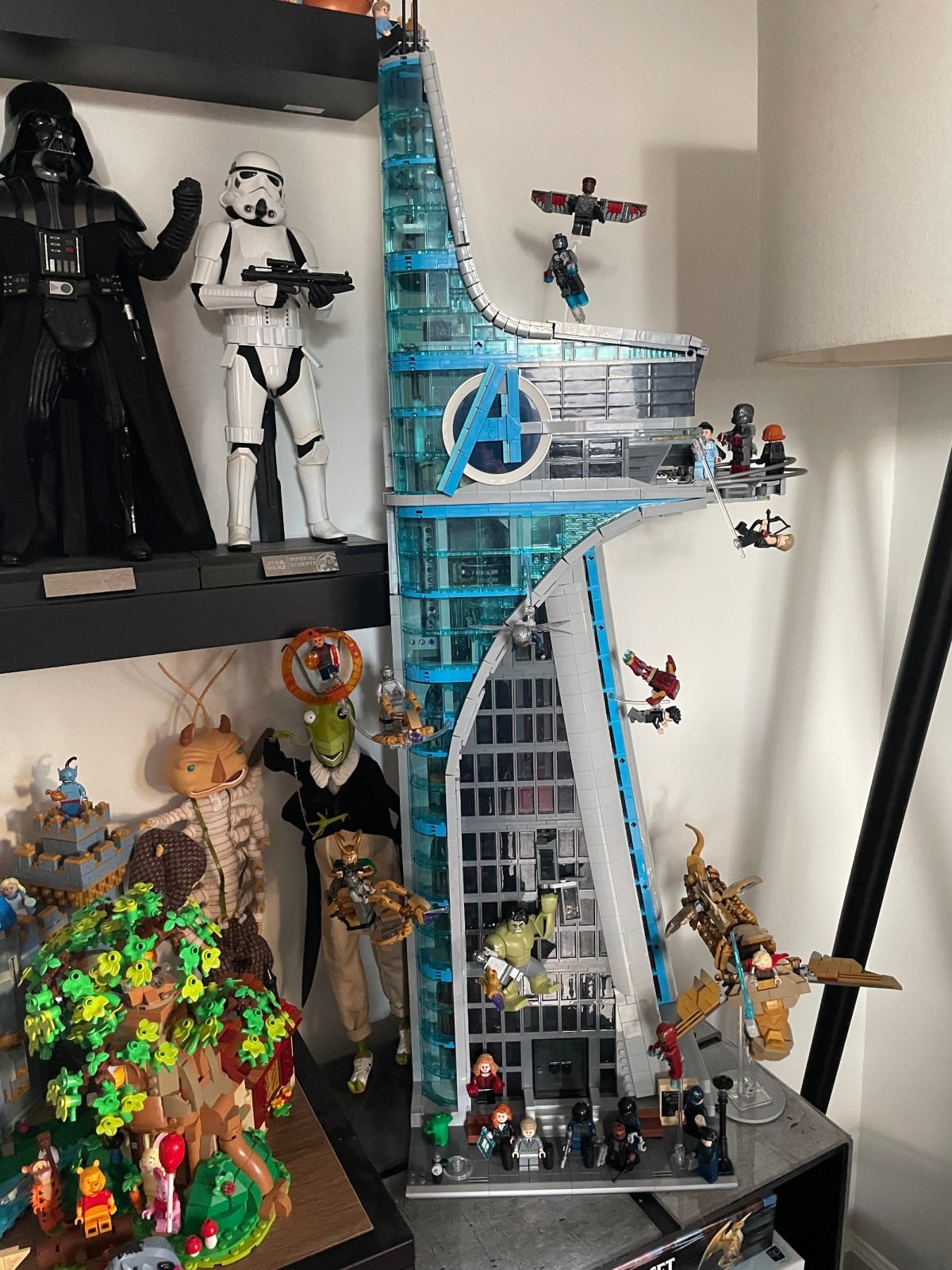 LEGO Avengers Tower surrounded by other toys, with LEGO Marvel minifigs surrounding it