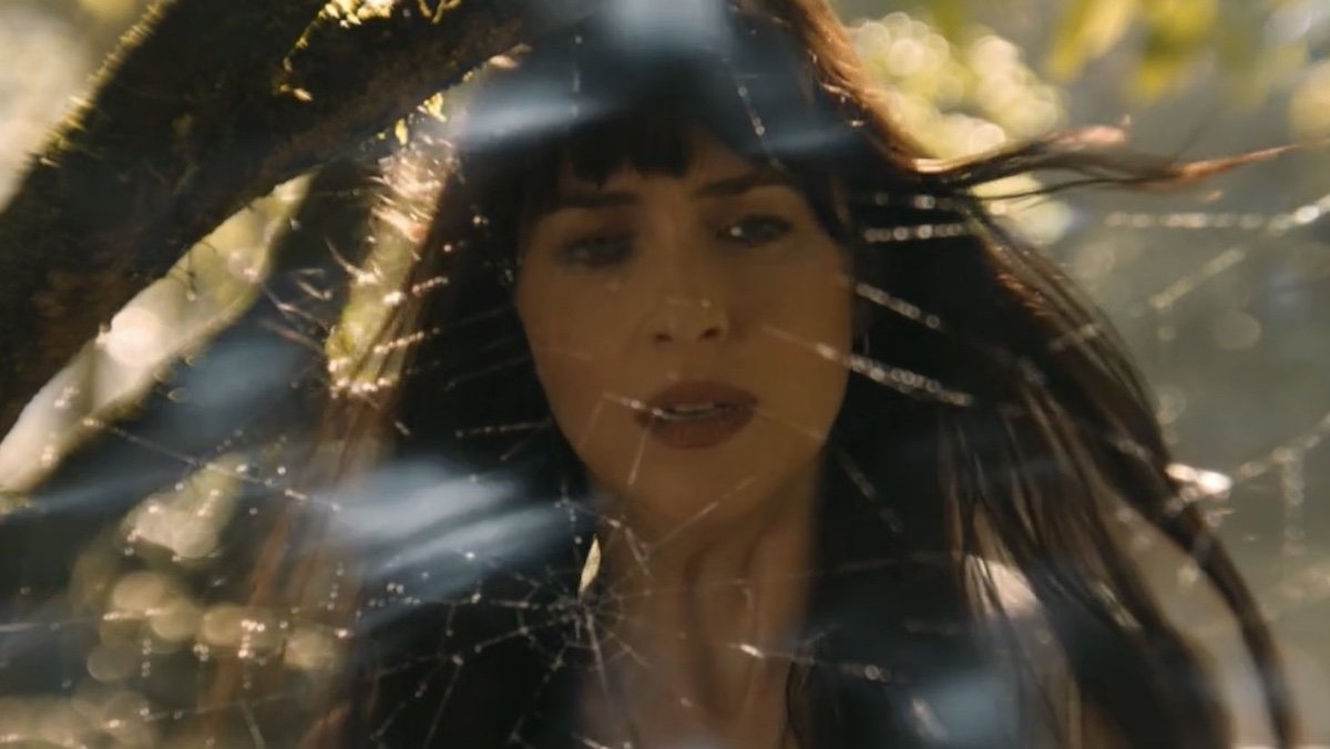 Dakota Johnson stands behind a giant spider web in Madame Web