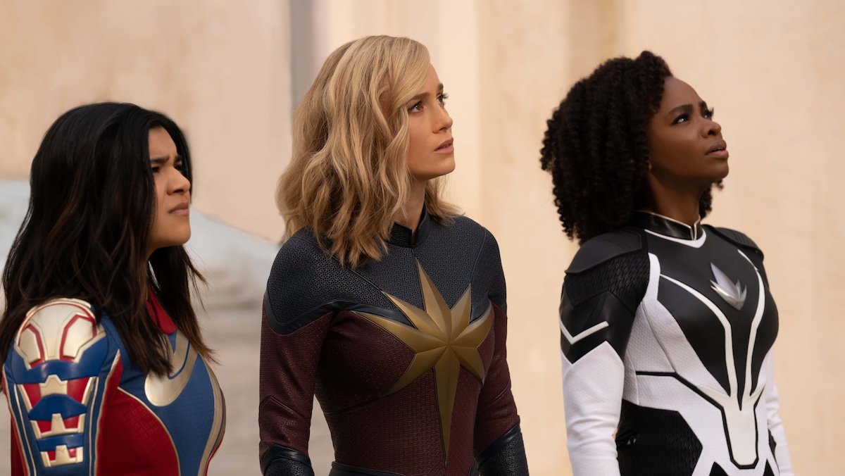 Kamala Khan, Carol Danvers, and Monica Rambeau all in their superhero costumes looking off to the side in The Marvels